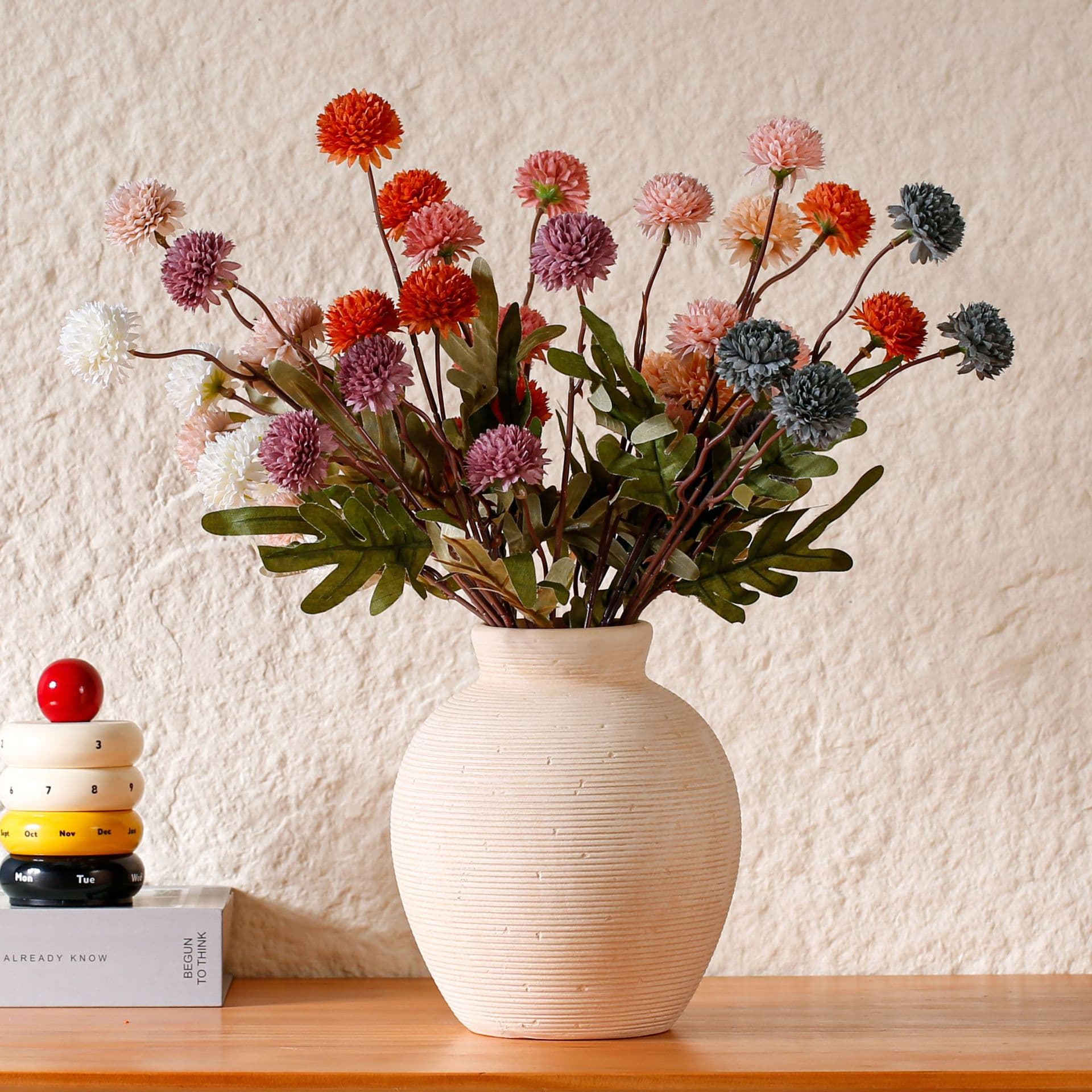 Cream textured ceramic vase styled with red and pink stems