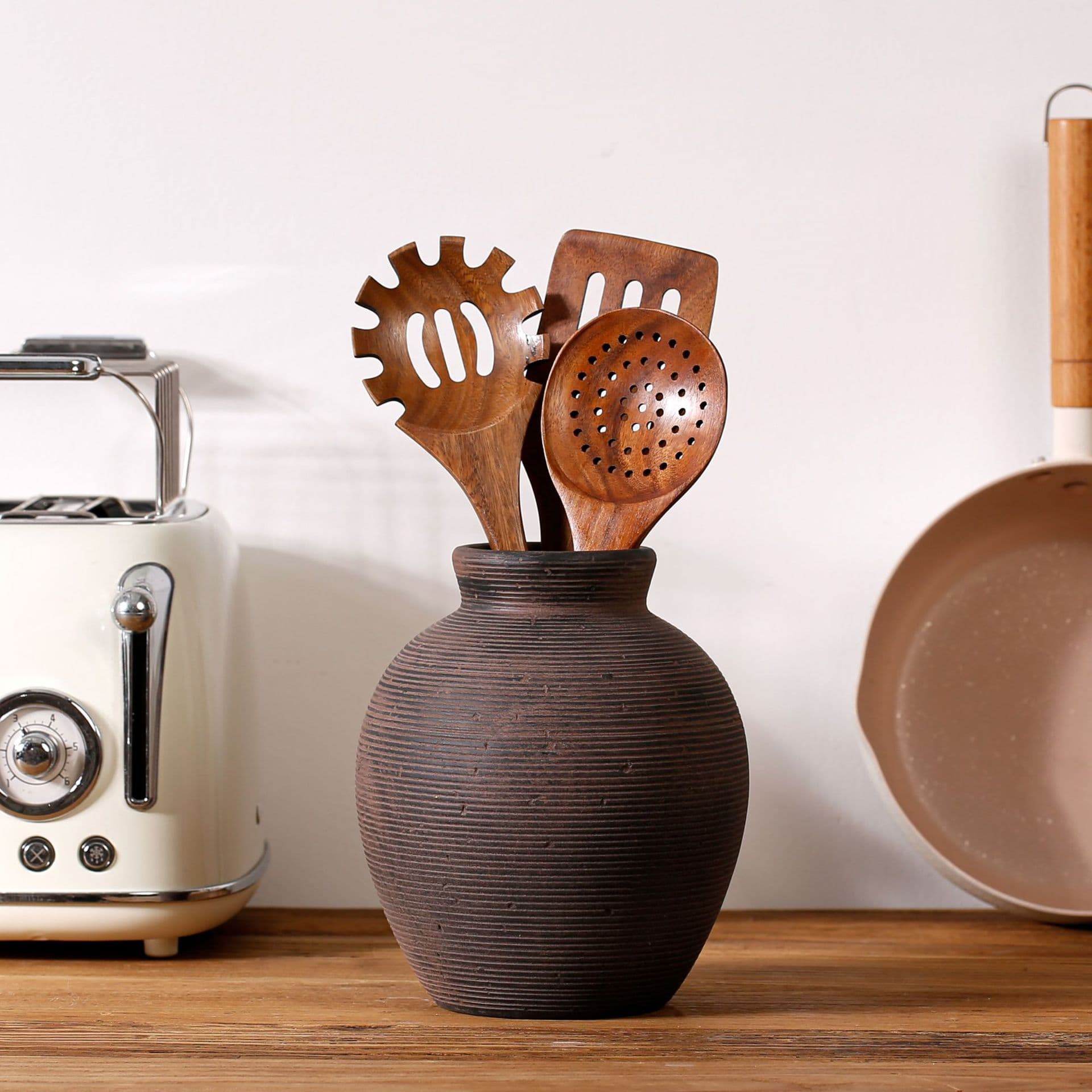 Dark textured ceramic vase styled with wooden utensils